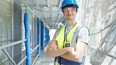 Kollarını kavuşturmuş genç İspanyol mimar inşaat alanında baş parmak hareketi yapıyor.