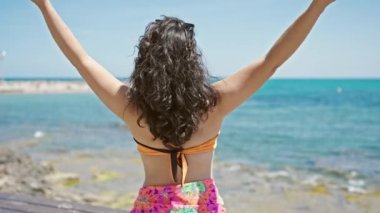 Genç ve güzel İspanyol kadın turist sahilde kendine güvenen bikini giyiyor.