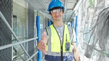 Genç İspanyol mimar inşaat alanında kendine güvenen bir şekilde el sıkışıyor.