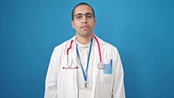 年轻的惊慌失措的男医生 手托着胸膛在孤零零的蓝色背景下宣誓 — 图库视频影像