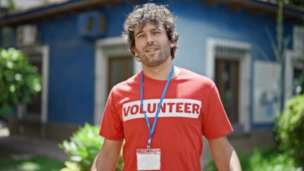 Junger Hispanischer Aktivist Zeigt Auf Freiwillige Uniform Und Lächelt Park — Stockvideo