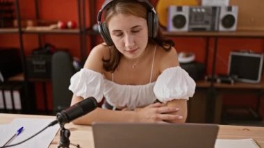 Genç bayan radyo muhabiri, radyo stüdyosunda çalışırken gülümsüyor.