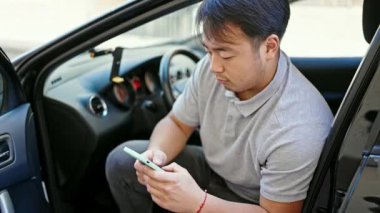 akıllı telefon kullanarak caddede arabada oturarak.