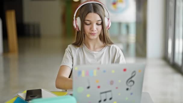 図書館で勉強するラップトップとヘッドフォンを使用して若い美しい少女の学生 — ストック動画