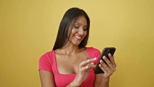 スマートフォンを使用している若いラテン系女性は 孤立した黄色の背景に驚きました — ストック動画