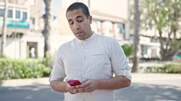 Young Hispanic Man Using Smartphone Park — Vídeo de Stock