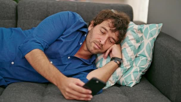 Jovem Hispânico Usando Smartphone Deitado Sofá Cansado Casa — Vídeo de Stock