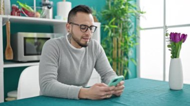 Yemek odasındaki masada oturan akıllı telefonu kullanan İspanyol adam.