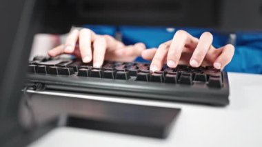 Genç İspanyol adam ofisteki klavyede bilgisayar kullanıyor.