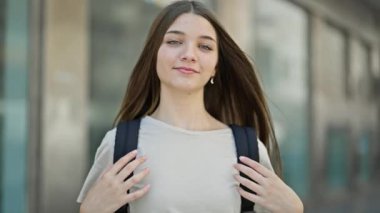 Sokakta kendine güvenen güzel bir kız öğrenci sırt çantası takıyor.