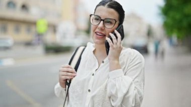Genç ve güzel İspanyol kadın caddede telefonla konuşuyor.