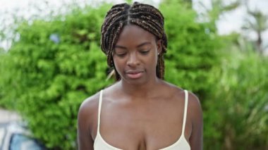 Afro-Amerikalı kadın parkta kendinden emin bir şekilde gülümsüyor.