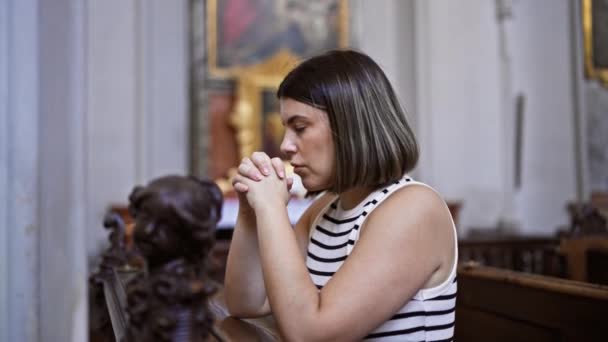 在维也纳奥古斯丁教堂的教堂长椅上祈祷的年轻美丽而惊慌的女人 — 图库视频影像