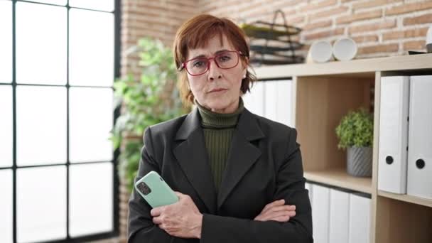 Mature Hispanic Woman Business Worker Serious Face Holding Smartphone Office — Stock Video