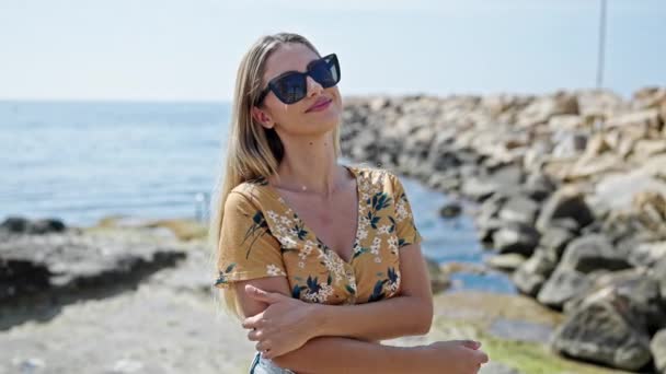 Junge Blonde Frau Lächelt Selbstbewusst Mit Sonnenbrille Und Verschränkten Armen — Stockvideo