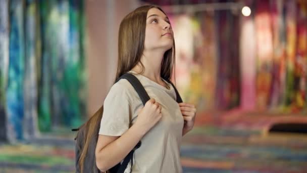 アートギャラリーで笑顔を見ながらバックパックを着た若い美しい少女の学生 — ストック動画