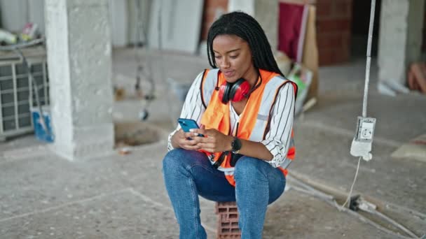 Afrikansk Amerikansk Kvinna Byggare Med Hjälp Smartphone Vilar Byggarbetsplatsen — Stockvideo