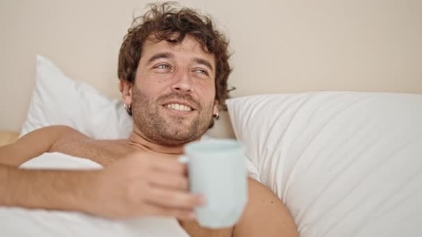 Genç Spanyol Adam Yatakta Üstsüz Uzanıp Yatak Odasında Kahve Içiyor — Stok video