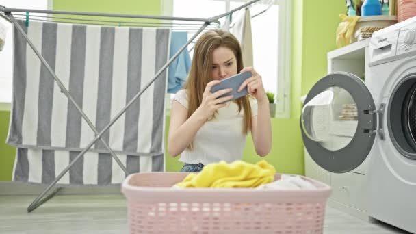 洗濯室でビデオゲームをプレイしている若い金髪の女性 — ストック動画