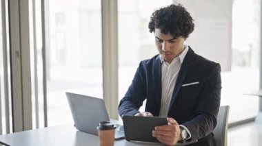 Young latin man business worker using laptop and touchpad at office