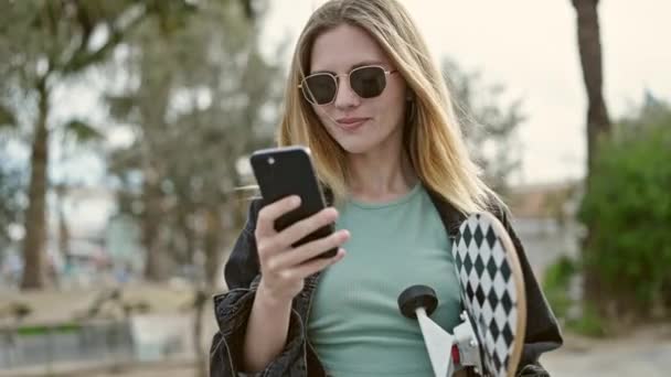 Mladá Blondýna Žena Drží Brusle Pomocí Smartphone Parku — Stock video