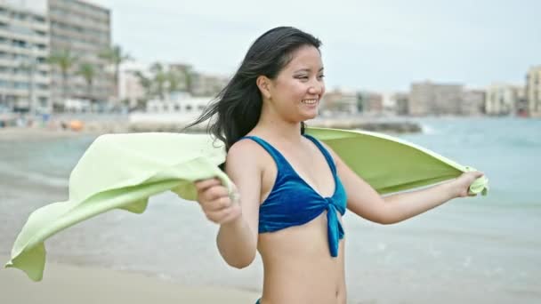 若い中国人女性観光客はビーチでビキニとタオルを着用して自信を持って微笑みます — ストック動画