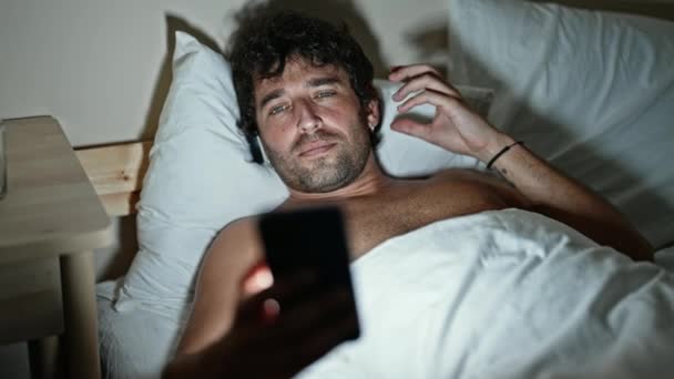 Молодий Іспаномовний Чоловік Дивиться Відео Смартфон Лежачи Ліжку Спальні — стокове відео