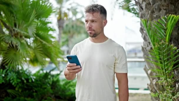Νεαρός Που Χρησιμοποιεί Smartphone Σοβαρή Έκφραση Στο Πάρκο — Αρχείο Βίντεο
