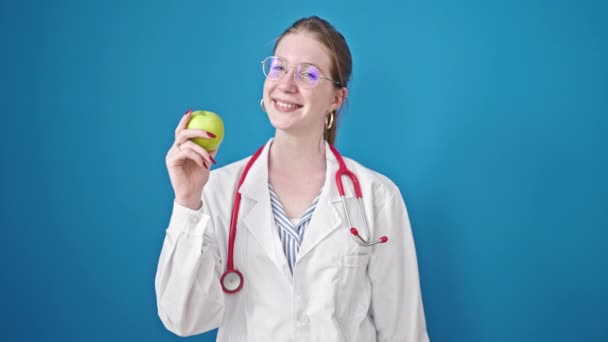 Młoda Blondynka Lekarz Uśmiecha Się Pewnie Trzymając Jabłko Nad Odizolowanym — Wideo stockowe