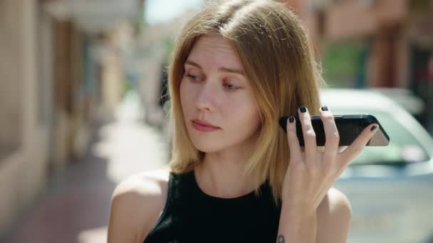 若いですブロンド女性リッスンにボイスメッセージとともに深刻な顔でストリート — ストック動画