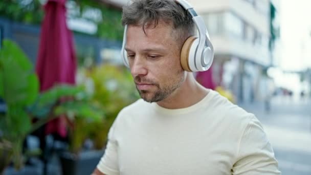 Sokakta Ciddi Yüzlü Kulaklıkları Çıkaran Genç Bir Adam — Stok video