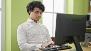 Ofiste çalışan genç Latin iş adamı bilgisayar kullanıyor.