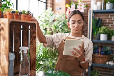 Çiçekçide kuşkulu bir ifadeyle not defteri okuyan güzel İspanyol kadın.