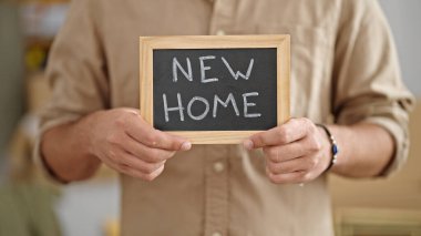 Yeni evinde tahtası olan Latin asıllı genç bir adam.