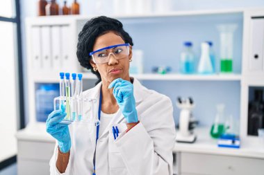 Orta yaşlı İspanyol kadın, laboratuvarda çalışıyor. Ciddi yüz ifadesi var. Çene ve çeneyle ilgili sorular soruyor. 