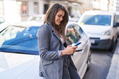 Sokakta akıllı telefon kullanan kendine güvenen genç bir kadın.