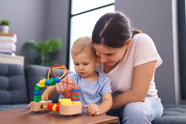 Anne ve oğlu evde oynarken kendinden emin gülümsüyor.