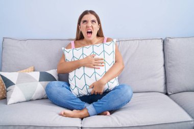 Kanepede oturan genç sarışın kadın kızgın ve kızgın bağırıyor öfkeyle bağırıyor.. 