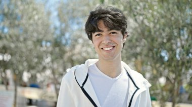 Parkta kendinden emin gülümseyen İspanyol genç adam.