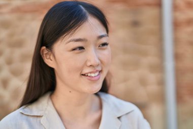 Çinli kadın gülümseyerek caddenin kenarına bakıyor.