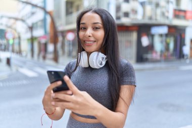 Young arab woman smiling confident using smartphone at street