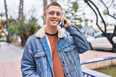 Genç İspanyol adam gülümsüyor. Parktaki akıllı telefondan konuşuyor.