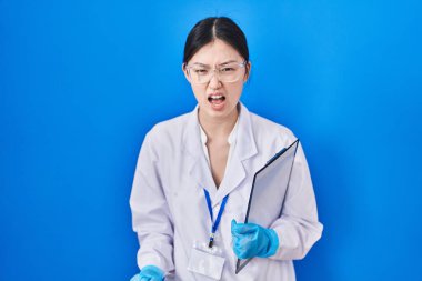 Bilim adamlarının laboratuvarında çalışan Çinli genç bir kadın kızgın ve kızgın bağırıyor öfkeyle bağırıyor. öfke ve agresif konsept. 