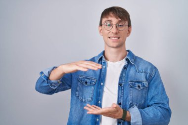 Beyaz, sarışın, gözlüklü, elinde kocaman bir işaret olan bir adam. Ölçü sembolü. Kameraya bakıp gülümsüyor. ölçüm kavramı. 