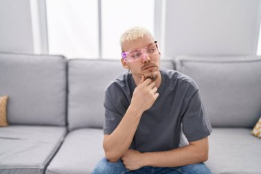 Sanal gerçeklik gözlüğü takan genç beyaz bir adam ciddi bir yüzle eli çenesinde soru soran kafa karıştırıcı bir fikir hakkında düşünceli. 