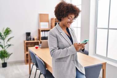 Ofiste akıllı telefon kullanan Afrikalı Amerikalı iş kadını.