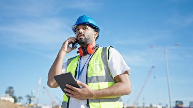 Afro-Amerikalı inşaatçı akıllı telefondan konuşuyor.