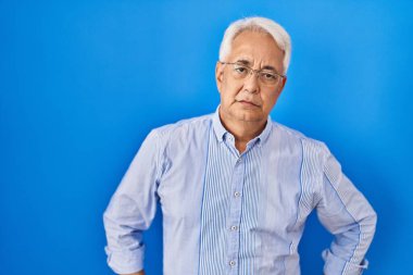 Hispanic senior man wearing glasses skeptic and nervous, frowning upset because of problem. negative person. 