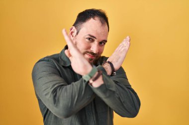Ayrıca sarı arka planda duran sakallı, İspanyol bir adam. Reddedilmiş yüz ifadesi. Kollarını kavuşturup negatif işaret veriyor. 