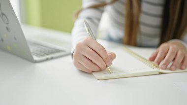 Kütüphanede dizüstü bilgisayar kullanarak notlar alan güzel İspanyol bir kız öğrenci.